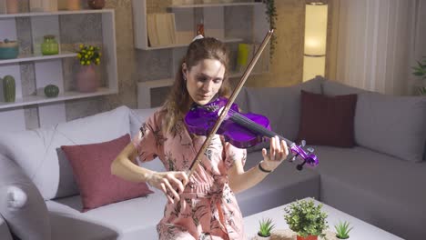 Young-woman-playing-the-violin-alone-in-the-living-room-at-home.